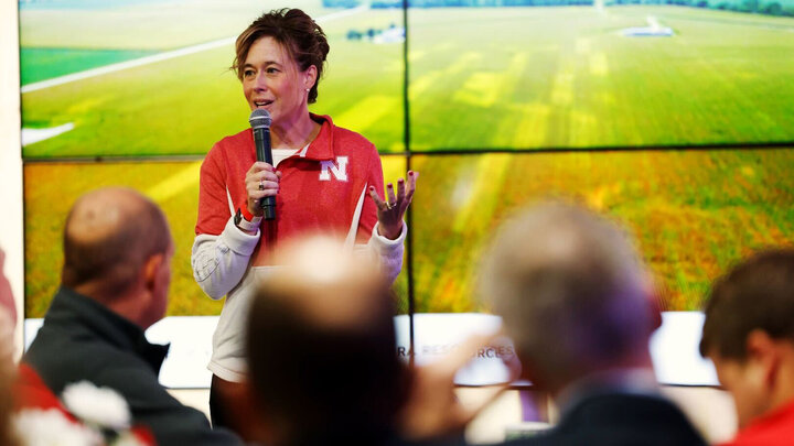 Tiffany Heng-Moss, Harlan Vice Chancellor for the Institute of Agriculture and Natural Resources and University of Nebraska vice president, speaks into a microphone as several people watch.
